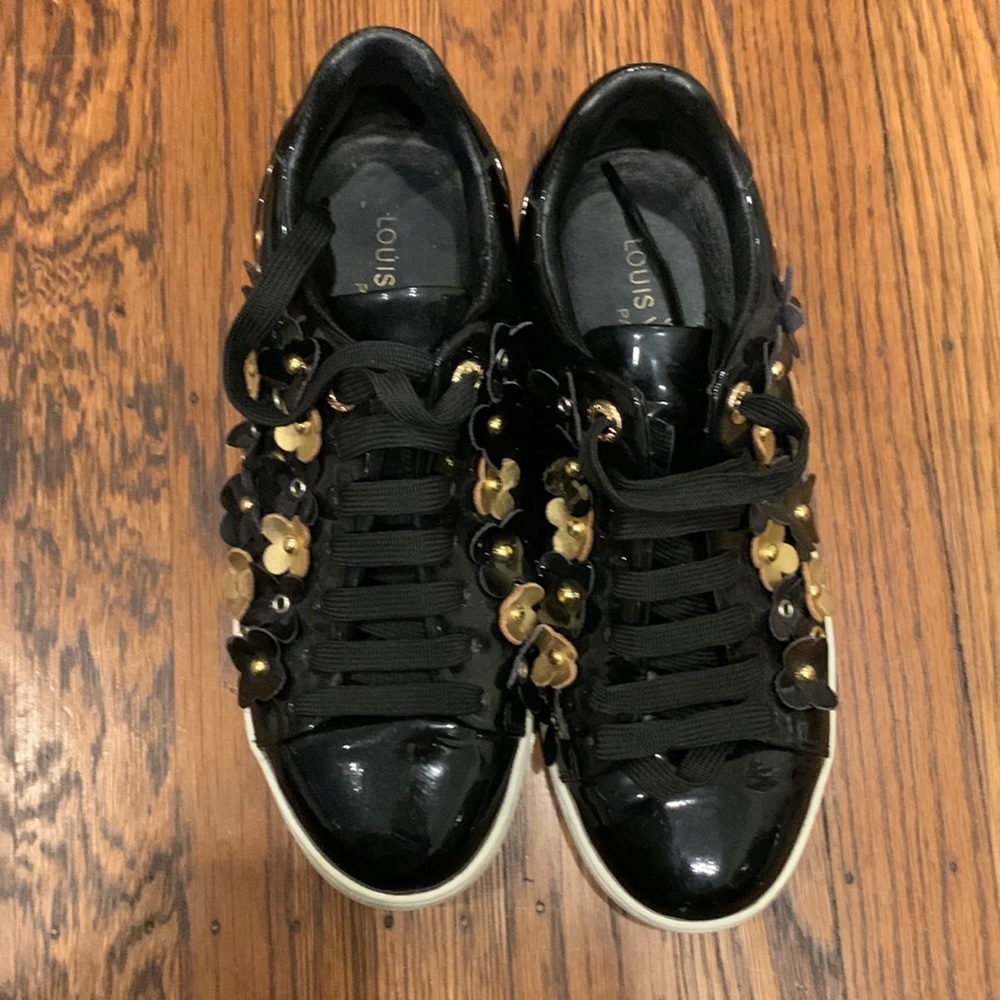 Black patent leather sneakers with black and gold flowers.